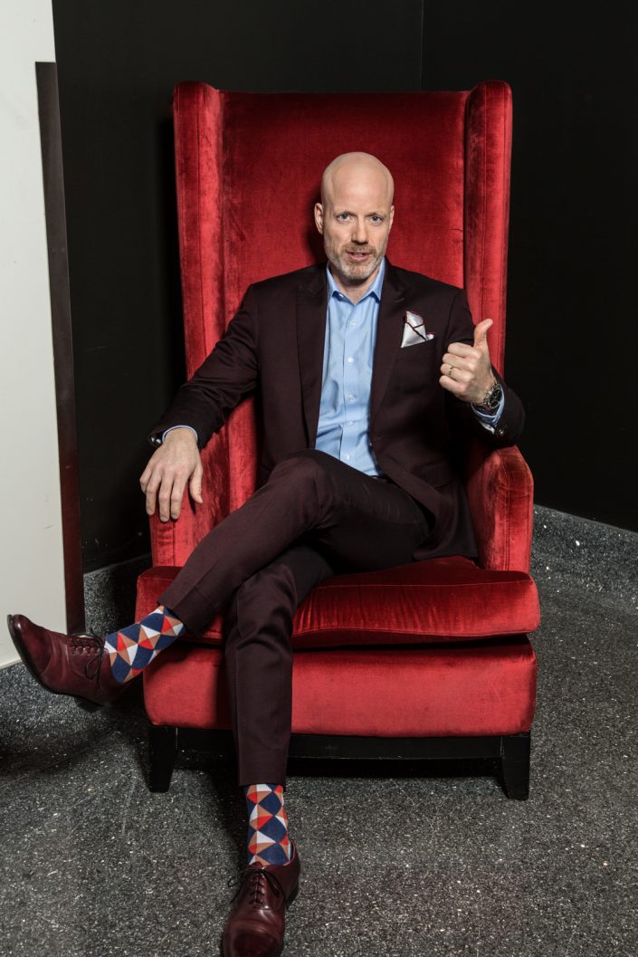 John Scholes in red chair for business photography 0O7C7292