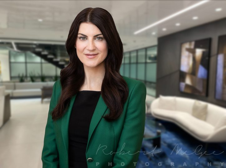 Female lawyer with long dark hair in green jacket, professional headshot in Toronto office foyer
