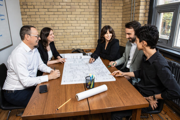 Candid photo of architectual team reviewing building plans during project meeting in Toronto