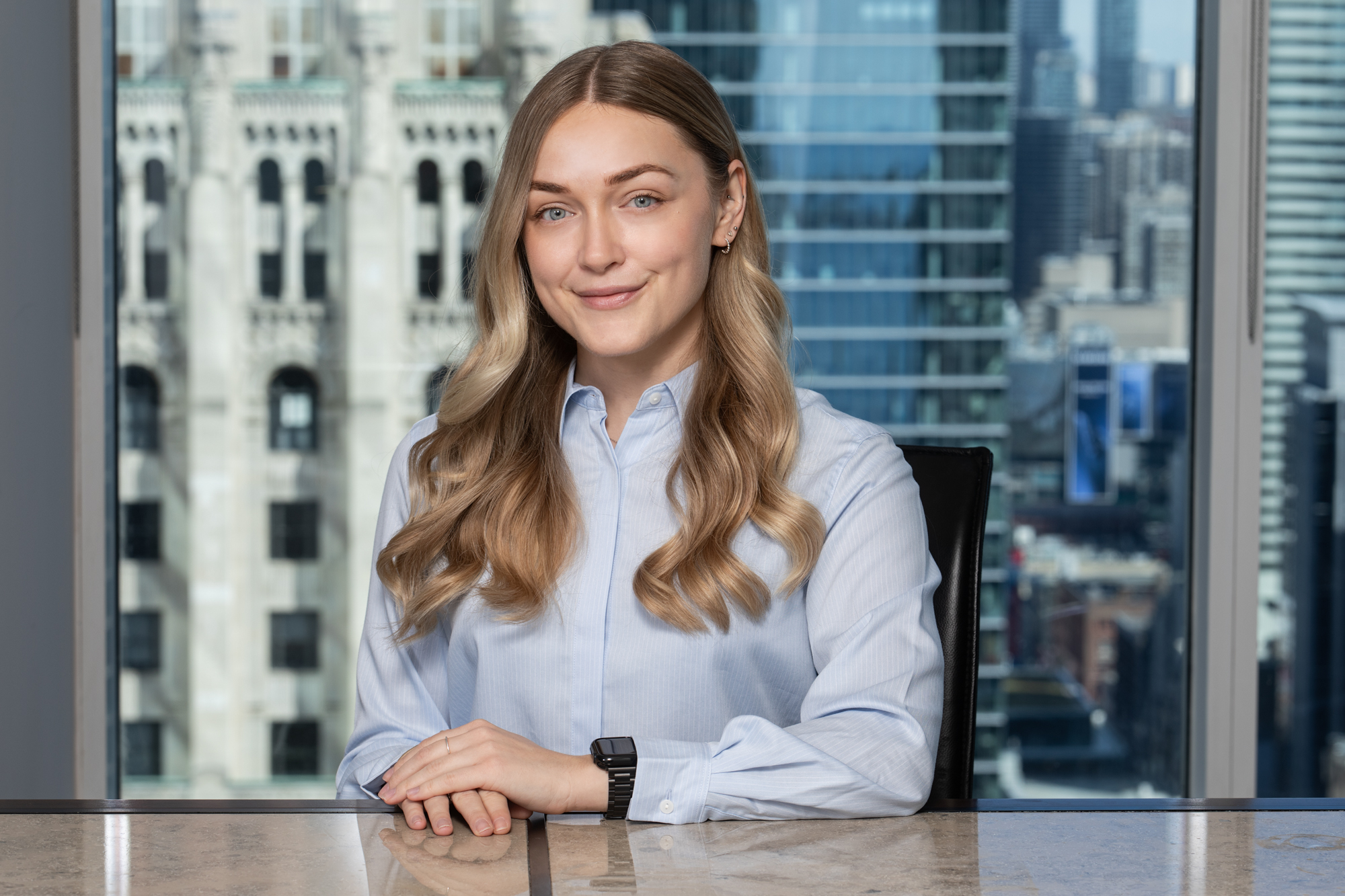 professional headshot of young lawyer with Toronto skyline window view